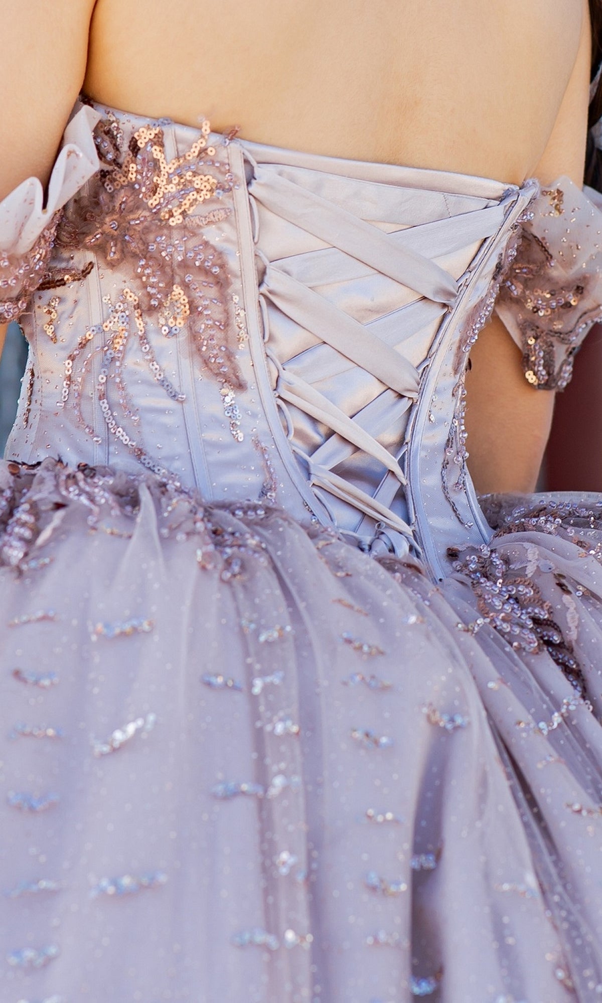 Close-up of the back of Quinceanera Ball Gown 8087J, showcasing lace-up ribbon, sequin embellishments on glitter tulle, and elegant off-the-shoulder sleeves in light purple.